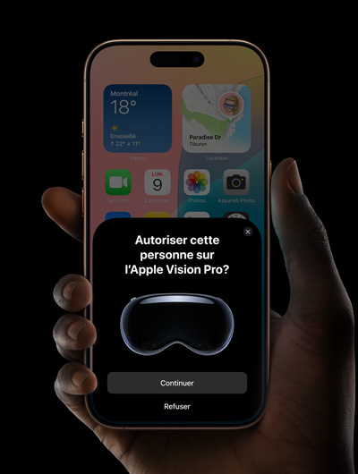 Une main tenant un iPhone. L’écran de l’iPhone affiche une fenêtre avec le message « Autoriser cette personne sur l’Apple Vision Pro? » et les boutons Continuer et Refuser.