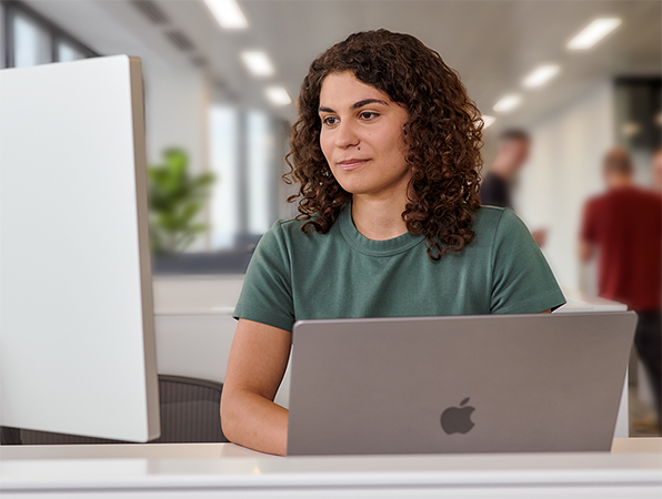 Apple 팀원이 사무실에서 MacBook과 Studio Display를 사용하고 있음.