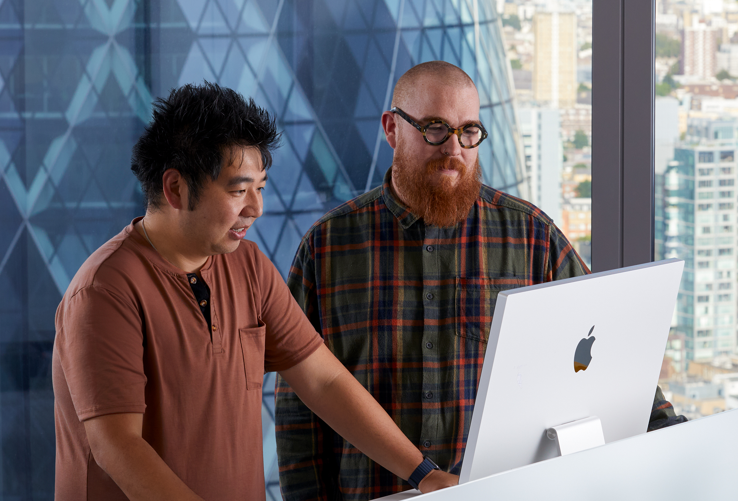 두 명의 Apple 동료들이 iMac을 사용하며 협력하고 있음.