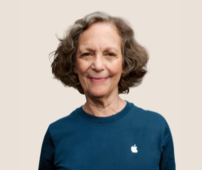 웨이브가 있는 어두운 회색 머리에 미소 짓고 있는 Apple Retail 팀원의 인물 사진.