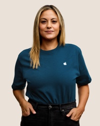 짙은 금발의 긴 머리에 미소 짓고 있는 Apple Retail 팀원의 인물 사진.