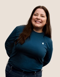 긴 검은 머리에 미소 짓고 있는 Apple Retail 팀원의 인물 사진.