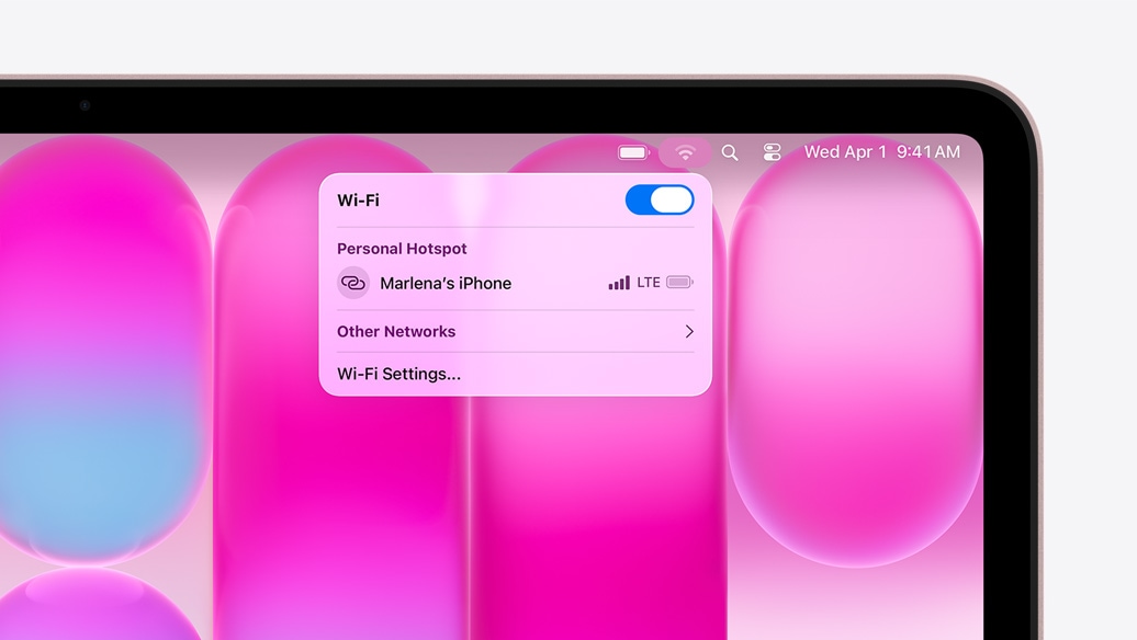 Ruměný MacBook Neo, v nabídce Wi‑Fi se zobrazuje připojení přes Osobní hotspot s nabídkou „Marlena’s iPhone“