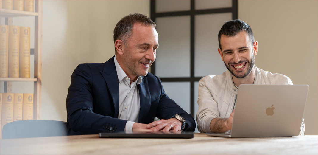 Deux hommes travaillant ensemble, regardant un MacBook ouvert.