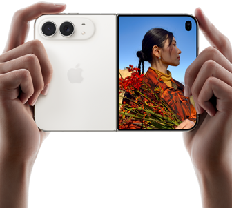 iPhone Duo, σε Λευκό του Άστρου, κρατιέται από δύο χέρια σε οριζόντιο προσανατολισμό, ξεδιπλωμένο, το αριστερό πλαίσιο δείχνει τις πίσω κάμερες Dual Fusion 48 MP, το δεξί πλαίσιο δείχνει ένα άτομο που το τραβούν φωτογραφία σε μια εξωτερική οθόνη, το άτομο μπορεί να δει το πρόσωπό του καθώς το τραβούν φωτογραφία με τη λειτουργία Duo Preview