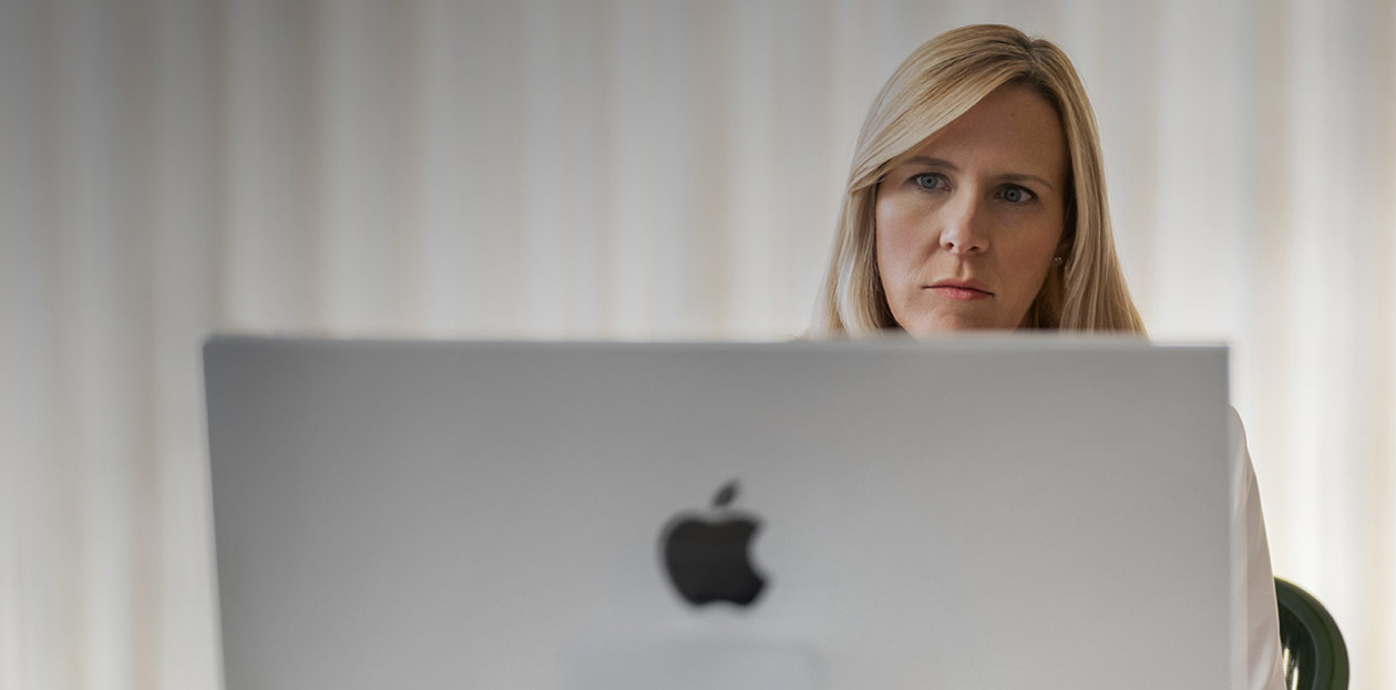 A provider looks at an iMac screen from behind her desk.
