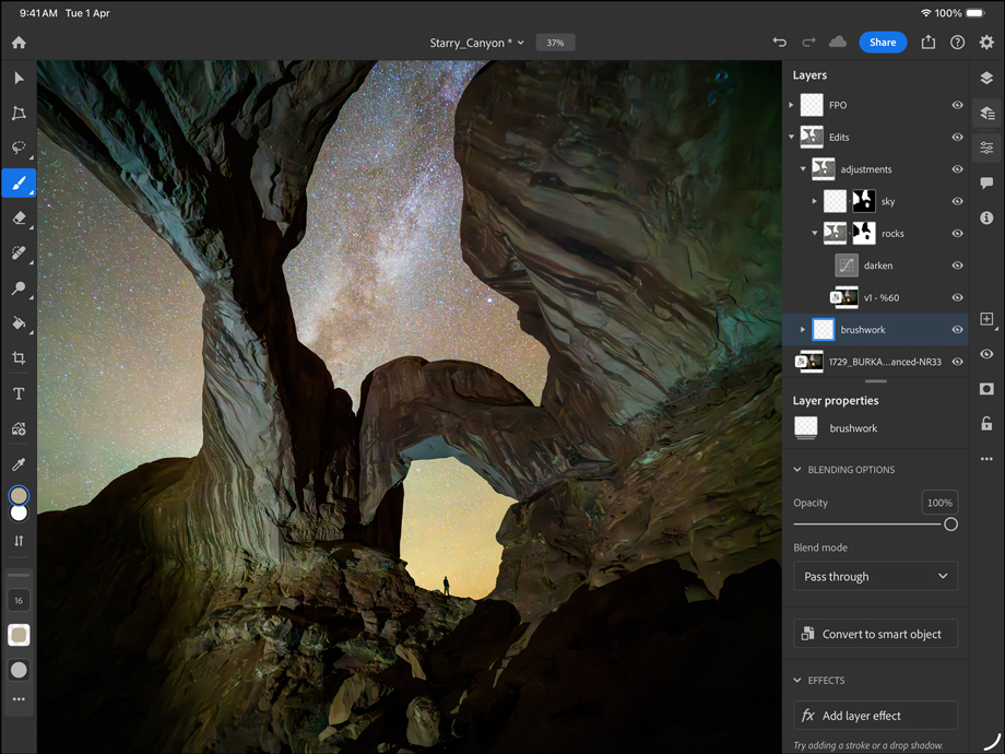 iPad Pro, front exterior, landscape orientation, space black colour, rounded corners, black display bezel, display showing a photograph being edited of a canyon and a star filled night sky, at right, editing layers, tools and effects visible including brushwork, adjustments and others