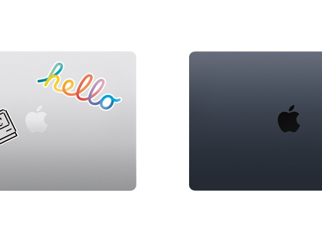 A top down view of two closed Mac laptops, one with stickers.