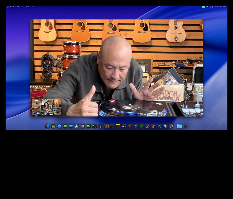 While on a video call on Studio Display XDR with Mac Studio tucked underneath, a person at a music store looks closely at a turntable