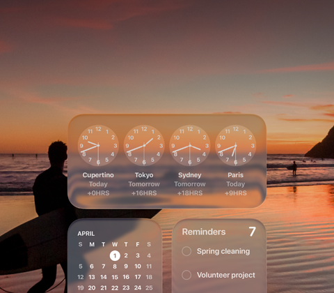 Liquid Glass Clock, Calendar, Reminders, and Weather widgets on macOS Tahoe screen over a scene of a surfer walking on the beach at sunset