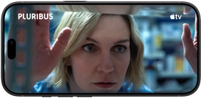 iPhone 18 Pro na šírku zobrazuje detailný záber ženy, ktorá si prezerá policu. Názov seriálu: Pluribus