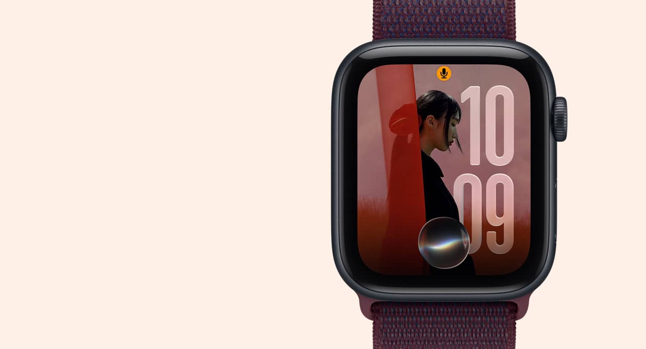 Apple Watch SE 3, 미드나이트 색상 알루미늄 케이스 및 사진 시계 페이스와 Siri 아이콘을 보여주는 모습. 오른쪽 옆면 외관에 Digital Crown 다이얼 및 버건디 색상 스포츠 루프 밴드의 모습