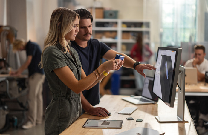 Une étudiante et un étudiant collaborent à partir d’un vrai modèle de composant tout en consultant un projet 3D sur un Studio Display; un MacBook, un Apple Pencil et un iPad sont posés sur la table