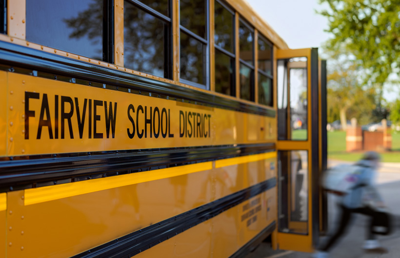 A close-up of the side of a Fairview School District school bus, as a child steps off the bus.