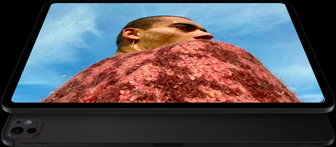 iPad Pro, face avant, orientation paysage, noir sidéral, angles arrondis, cadre d’écran noir, écran affichant la photo d’un homme en pull rouge sous un ciel bleu, en dessous, un autre iPad Pro, face arrière, orientation paysage, noir sidéral, système caméra pro, boutons d’augmentation et de diminution du volume