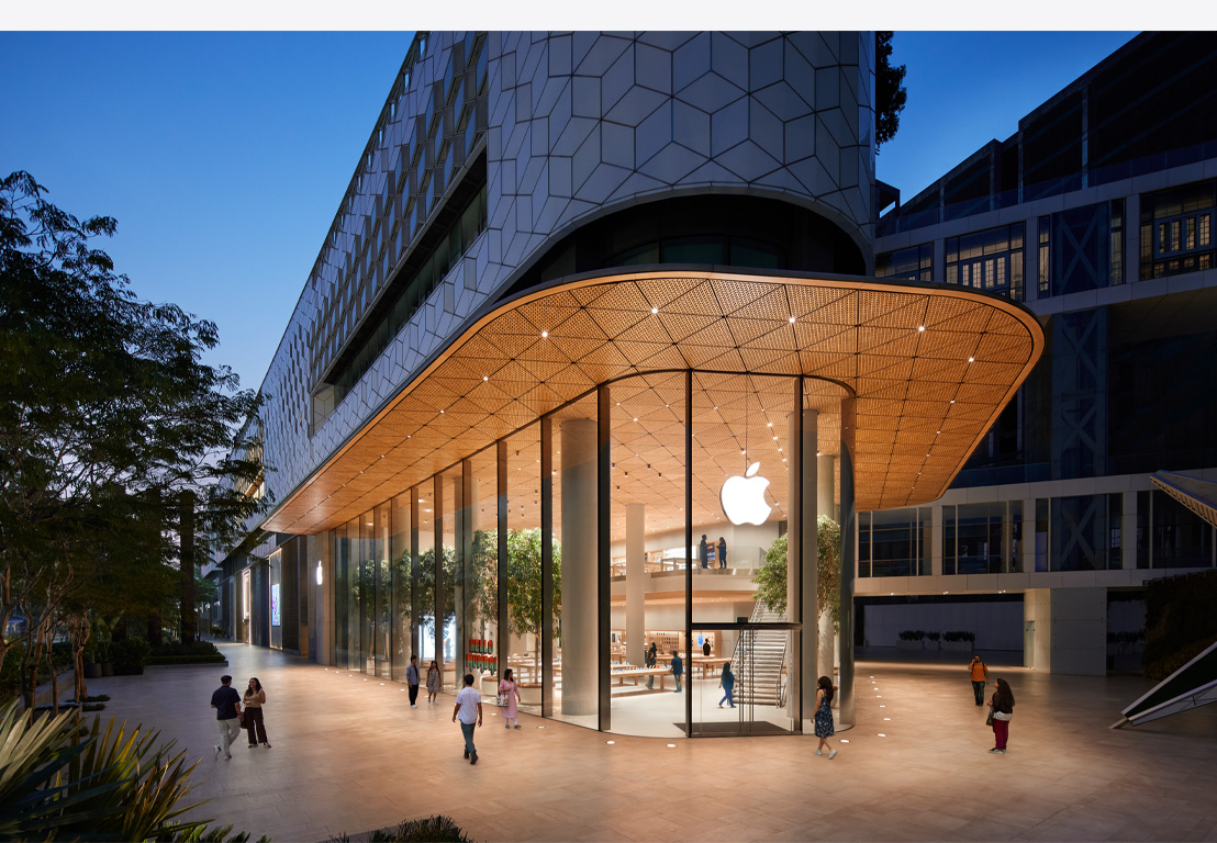 Магазин на Apple през нощта, стъклени витрини, осветени отвътре, лого на Apple в центъра на входната врата.