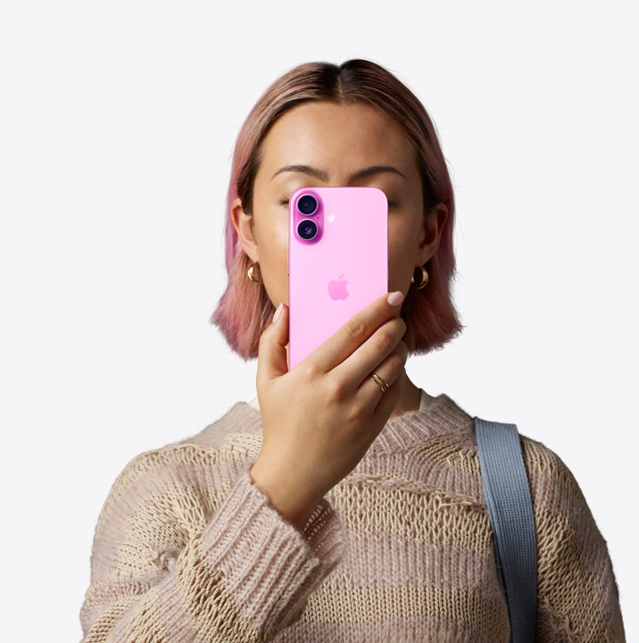 Човек, държащ iPhone16 в розово пред лицето си, показващ заден екстериор, система с две камери в горния ляв ъгъл.