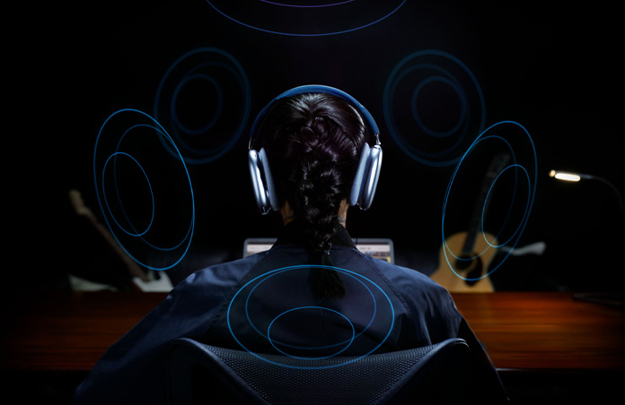 Back of a person’s head wearing Apple AirPods Max and graphics around their head indicating spatial audio