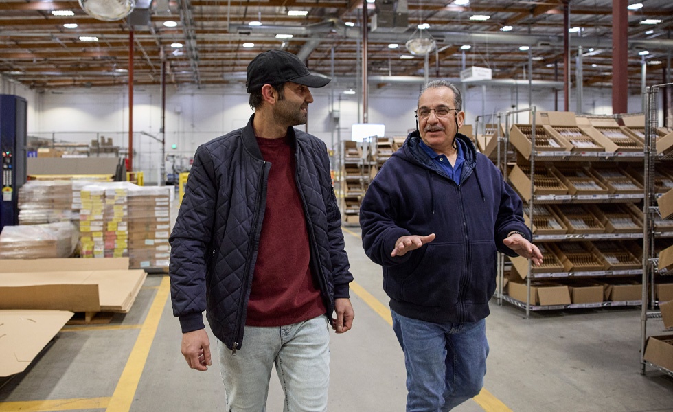 Two people share feedback as they walk a warehouse floor